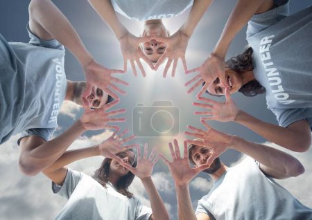 Téléchargez les photos : Équipe de bénévoles souriants debout en cercle mains sur fond de ciel - en image libre de droit