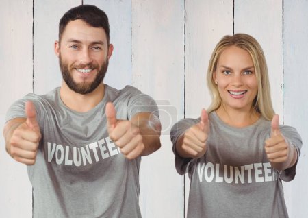 Photo for Couple of smiling volunteer thumb up against wooden background - Royalty Free Image