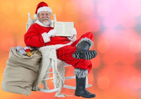 Téléchargez les photos : Père Noël souriant montrant le livre sur fond rouge flou - en image libre de droit