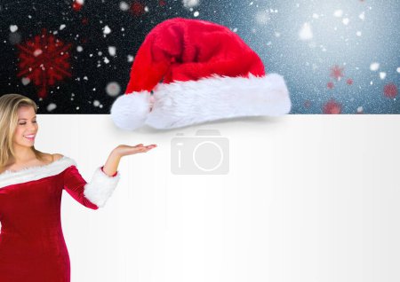 Téléchargez les photos : Belle femme montrant chapeau de Noël sur fond neigeux - en image libre de droit