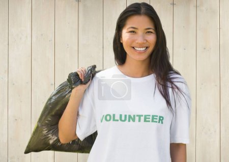 Téléchargez les photos : Volontaire souriant avec sac sur fond en bois - en image libre de droit