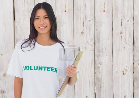 Photo for Smiling volunteer with notebook against wooden background - Royalty Free Image