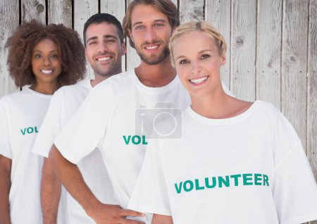 Téléchargez les photos : Groupe de bénévoles souriants sur fond de bois - en image libre de droit