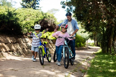 Foto de Padre e hijos de pie con bicicleta en el parque - Imagen libre de derechos