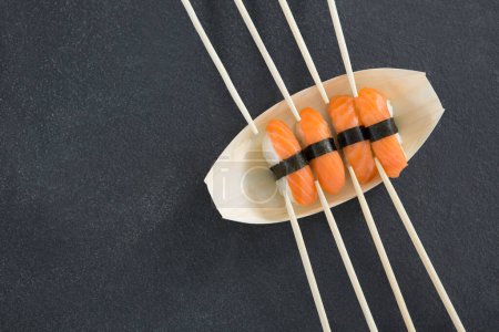 Photo for Sushi on boat shaped plate with chopsticks - Royalty Free Image