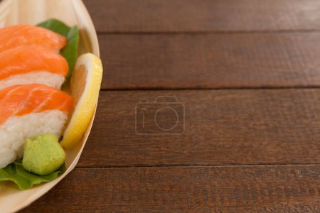Foto de Tres nigiri sushi servidos en plato de barco de madera - Imagen libre de derechos