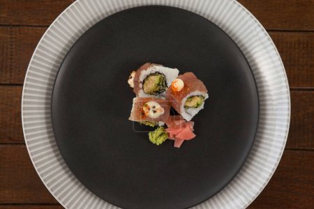 Téléchargez les photos : Trois sushis uramaki servis dans une assiette ronde noire - en image libre de droit