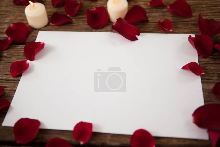 Foto de Vela de cera y papel en blanco rodeados de pétalos de rosa - Imagen libre de derechos