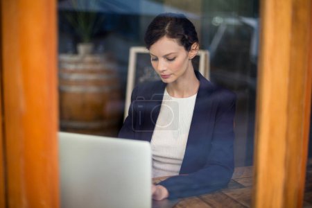 Téléchargez les photos : Confiant Businesswoman en utilisant un ordinateur portable dans le café - en image libre de droit