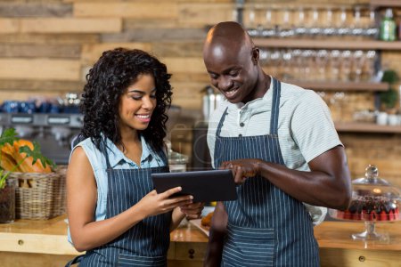 Photo for Smiling waiter and waitress using digital tablet at counter - Royalty Free Image