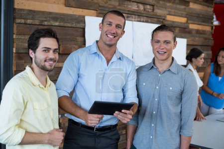 Téléchargez les photos : Dirigeants d'entreprise souriants debout au bureau avec tablette numérique - en image libre de droit
