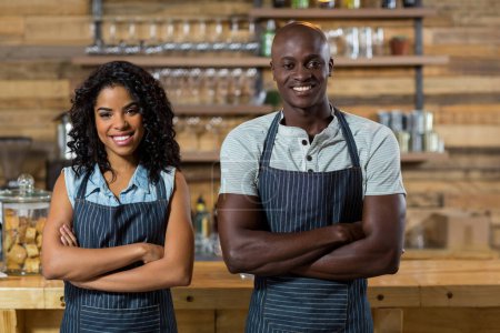 Photo for Portrait of smiling waiter and waitress standing with arms crossed at counter - Royalty Free Image