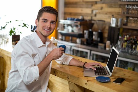 Foto de Hombre tomando café mientras usa el ordenador portátil - Imagen libre de derechos