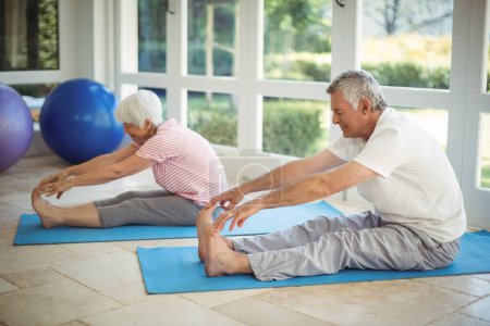 Téléchargez les photos : "Couple de personnes âgées effectuant des exercices d'étirement sur tapis d'exercice
" - en image libre de droit