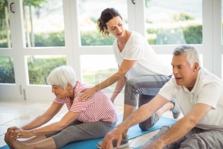 Photo for "Female trainer assisting senior couple in performing exercise" - Royalty Free Image