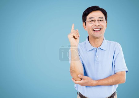 Téléchargez les photos : Happy Man levant le bras et souriant sur un fond bleu clair - en image libre de droit
