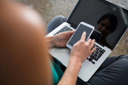 Téléchargez les photos : Femme exécutive utilisant un ordinateur portable et un téléphone portable au bureau - en image libre de droit