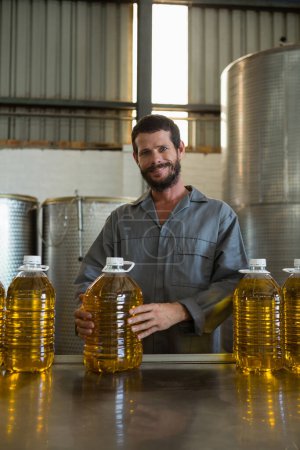 Téléchargez les photos : Ouvrier tenant une boîte d'huile d'olive en usine - en image libre de droit