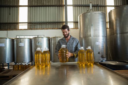 Téléchargez les photos : Travailleur examinant une boîte d'huile d'olive en usine - en image libre de droit