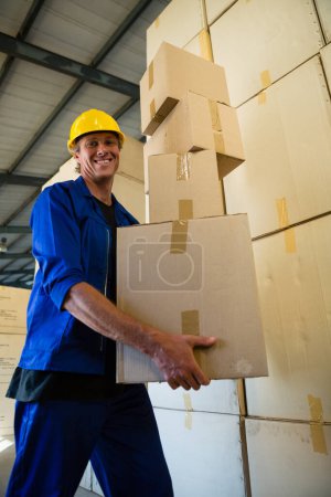 Foto de Trabajador sosteniendo cajas de cartón mientras camina en fábrica de aceitunas - Imagen libre de derechos