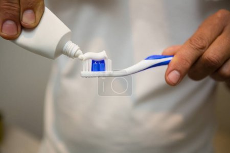 Téléchargez les photos : Mi-section de l'homme mettre du dentifrice sur la brosse à dents - en image libre de droit
