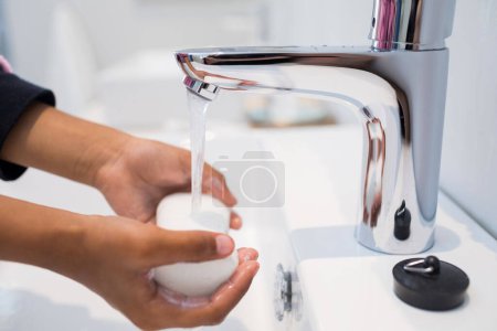 Téléchargez les photos : Fille lavage des mains dans lavabo salle de bains - en image libre de droit