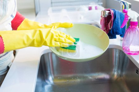 Photo for Woman washing plate with sponge in kitchen sink - Royalty Free Image