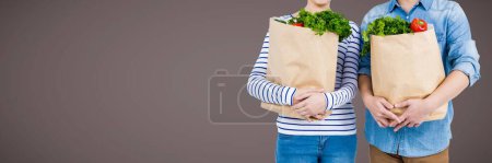 Photo for Couples mid sections with grocery bags against brown background - Royalty Free Image