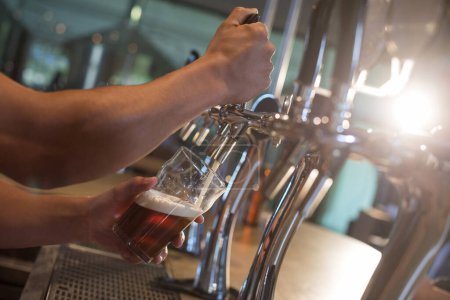 Téléchargez les photos : Barman versant de la bière du robinet - en image libre de droit