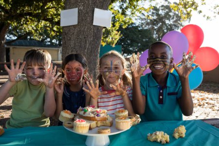 Foto de Niños alegres haciendo gestos mientras comen dulces en el parque - Imagen libre de derechos