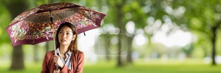 Téléchargez les photos : Femme millénaire avec parapluie à motifs contre les arbres verts flous - en image libre de droit