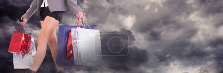 Téléchargez les photos : Femme faisant du shopping avec des sacs et des nuages sombres fond - en image libre de droit