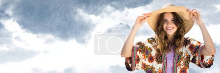 Foto de Mujer milenaria en ropa de verano sosteniendo sombrero contra el cielo nublado - Imagen libre de derechos