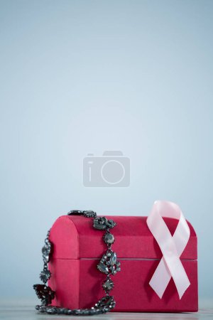 Photo for Close-up of pink Breast Cancer Awareness ribbon and jewelry on red box - Royalty Free Image