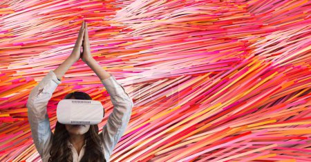 Foto de Auricular de mujer en VR levantando las manos contra líneas de color rosa de fondo - Imagen libre de derechos