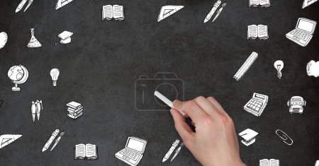 Photo for "Hand holding chalk surrounded by education graphics on blackboard" - Royalty Free Image