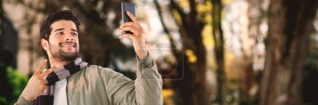 Téléchargez les photos : Image composite de l'homme souriant prenant selfie par téléphone portable sur fond blanc - en image libre de droit