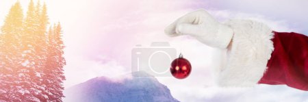 Téléchargez les photos : Père Noël en hiver tenant décoration boule de Noël - en image libre de droit