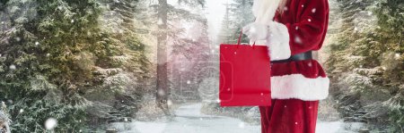 Photo for Santa with Winter landscape holding shopping bag - Royalty Free Image
