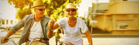 Téléchargez les photos : "heureux mature couple aller pour un vélo balade dans l 'ville
" - en image libre de droit