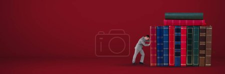 Téléchargez les photos : Homme d'affaires poussant des livres sur fond rouge - en image libre de droit