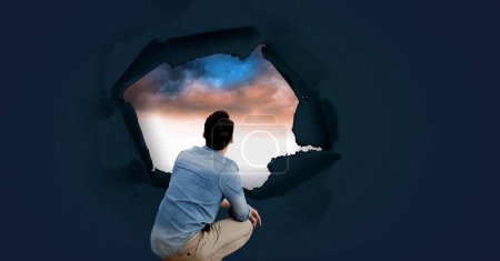 Foto de Hombre mirando a través de agujero de papel surrealista en el cielo - Imagen libre de derechos