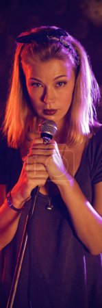 Photo for Confident female singer with drummer performing on illuminated stage in nightclub - Royalty Free Image