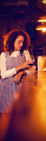 Foto de Mujer pensativa tomando vino tinto en el mostrador - Imagen libre de derechos