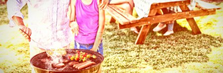 Téléchargez les photos : Grand-père et petite-fille préparant le barbecue pendant le repas en famille - en image libre de droit