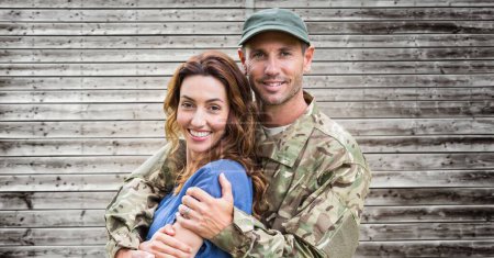 Photo for Soldier holding partner in front of wood - Royalty Free Image