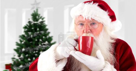 Photo for Santa drinking cup next to Christmas tree - Royalty Free Image