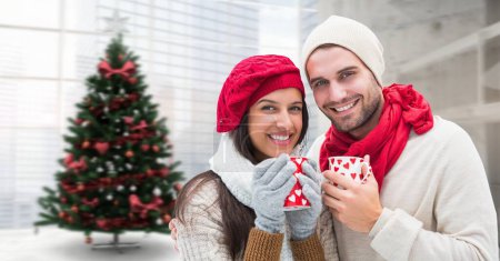 Téléchargez les photos : Couple d'hiver tasses à boire à côté de l'arbre de Noël - en image libre de droit