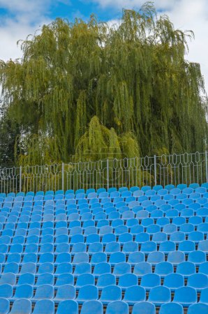 Téléchargez les photos : Stade vide avec des sièges et des arbres verts sur le fond - en image libre de droit