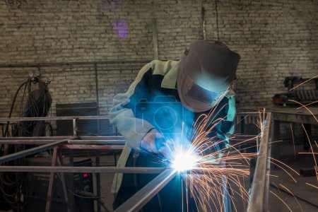 Photo pour "Soudeur soudant une pièce métallique dans un environnement industriel, portant un équipement de protection standard
." - image libre de droit
